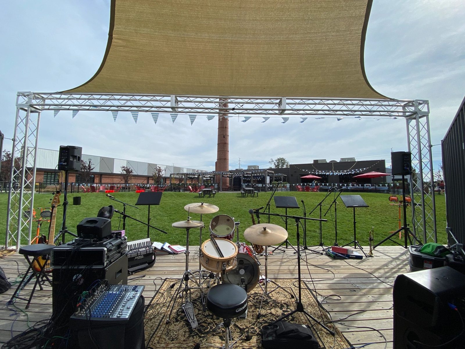 Outdoor festival stage with accordion, sax, drums, and Bavarian pennants